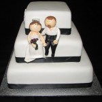 Black and white themed wedding cake with handmade bride and groom