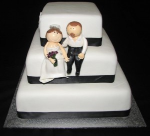 Black and white themed wedding cake with handmade bride and groom